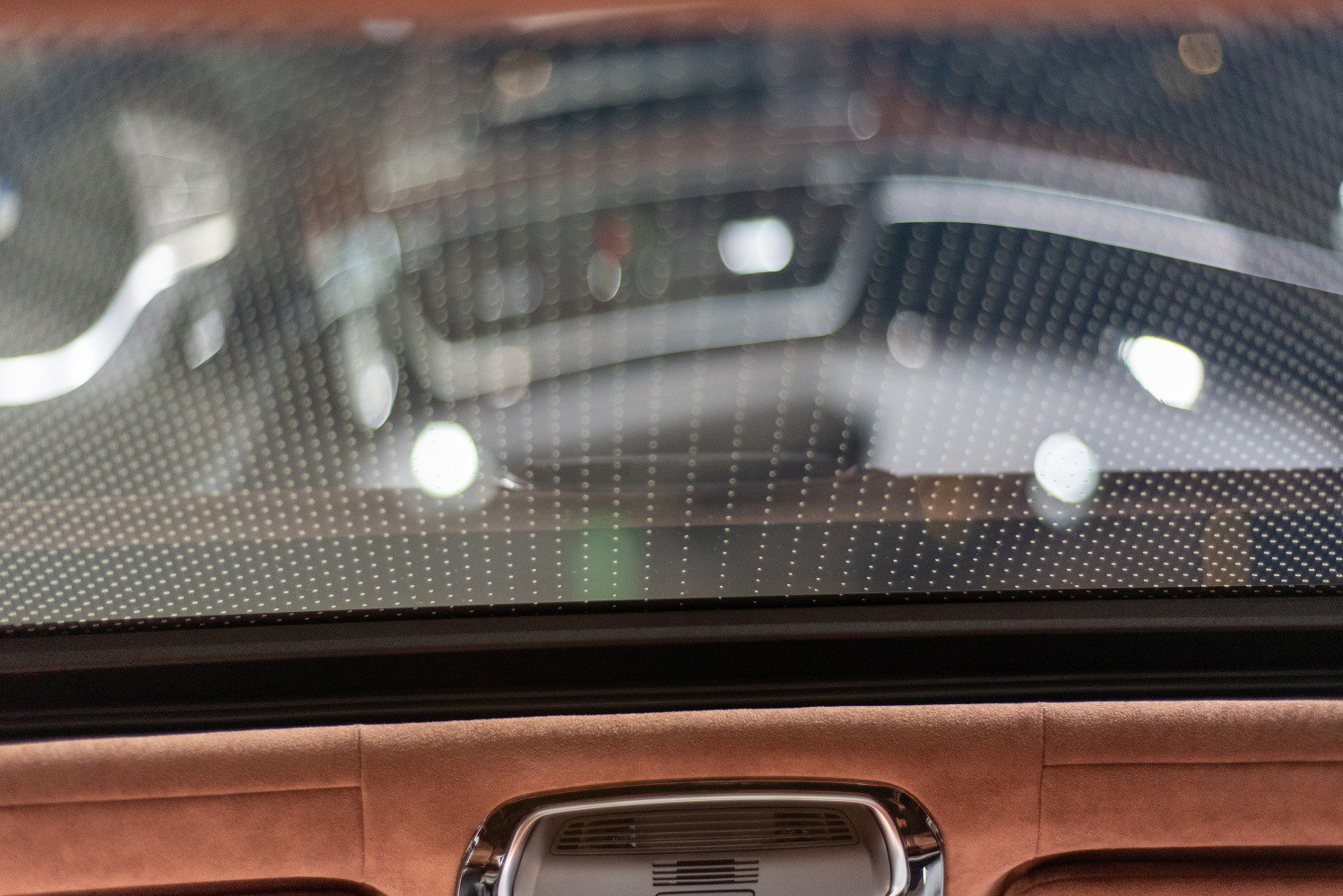 Rear window with defogger dots and brown suede headrest with ventilation