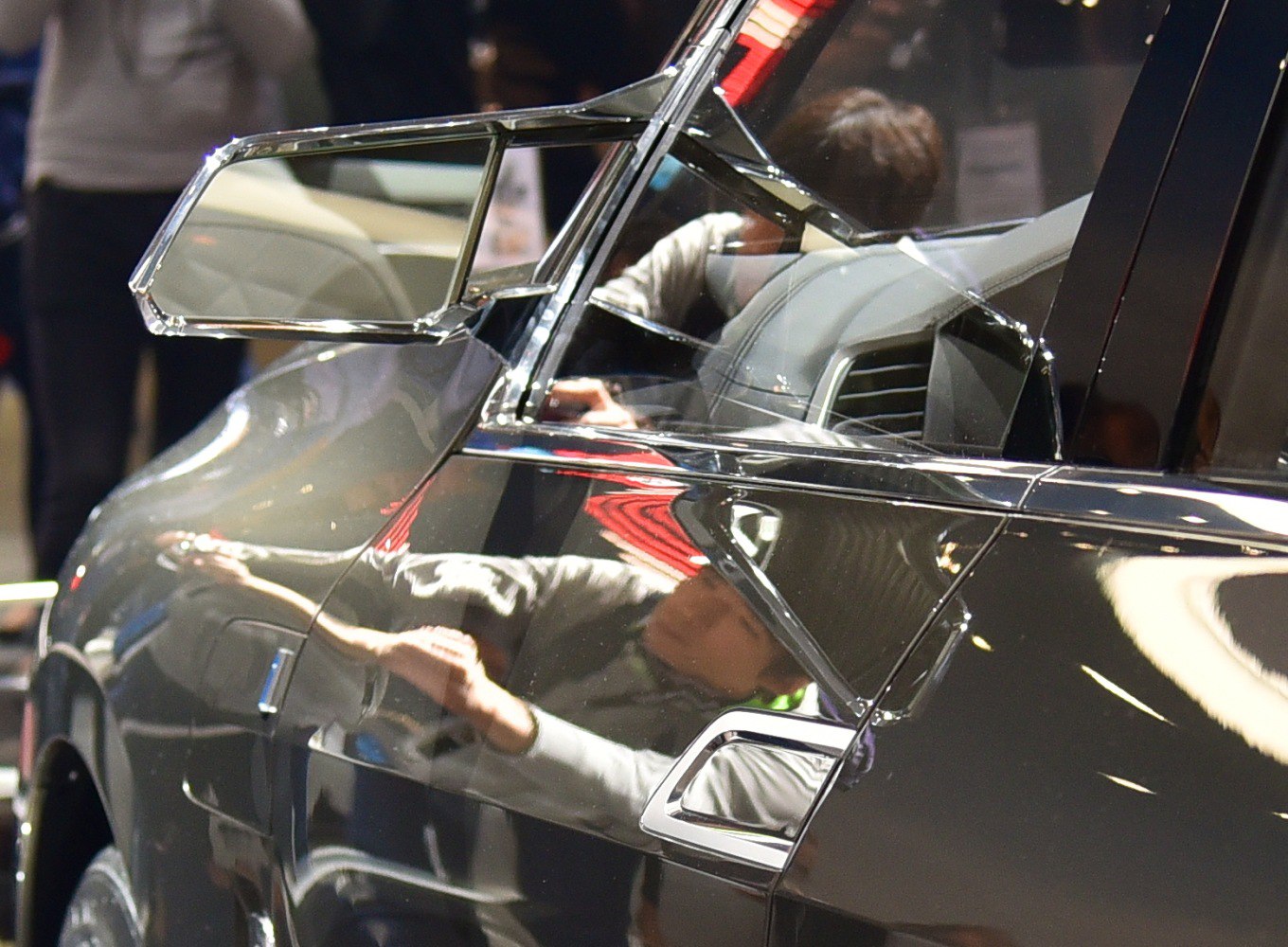 Close-up of side mirror and door with chrome trim on reflective black paint
