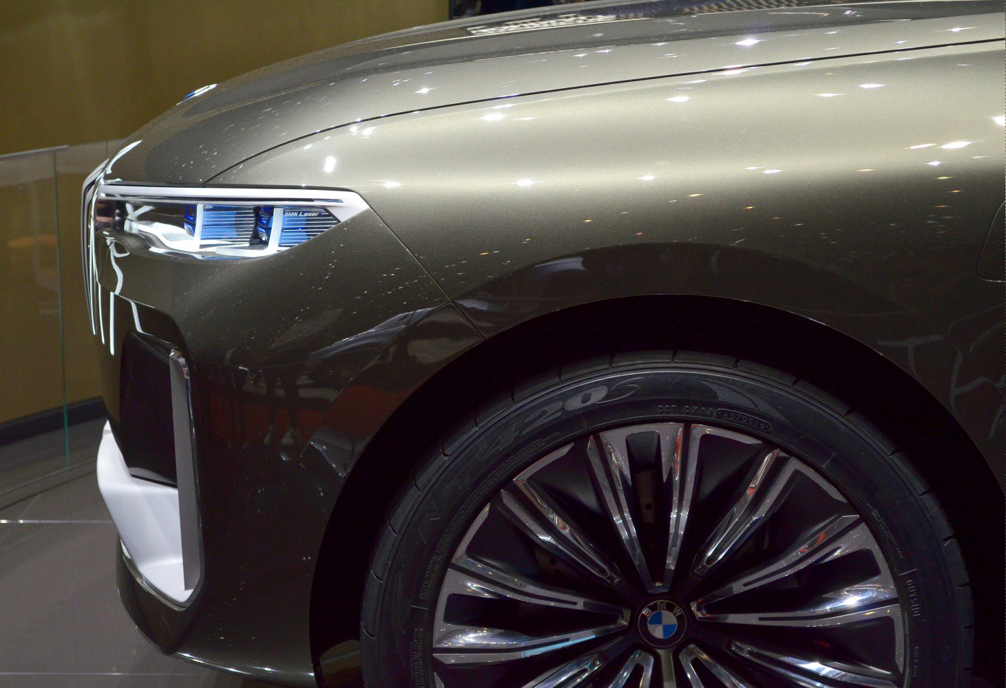 Close-up of front laser headlight and multi-spoke alloy wheel.