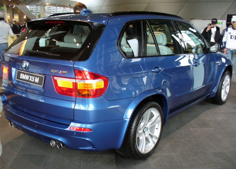 Rear and side profile of a blue SUV with distinctive taillights and quad exhausts