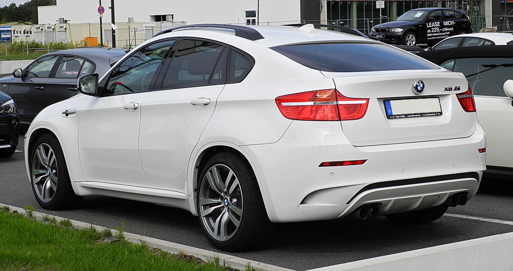 Rear side profile of a white SUV with dual exhaust and sporty taillights