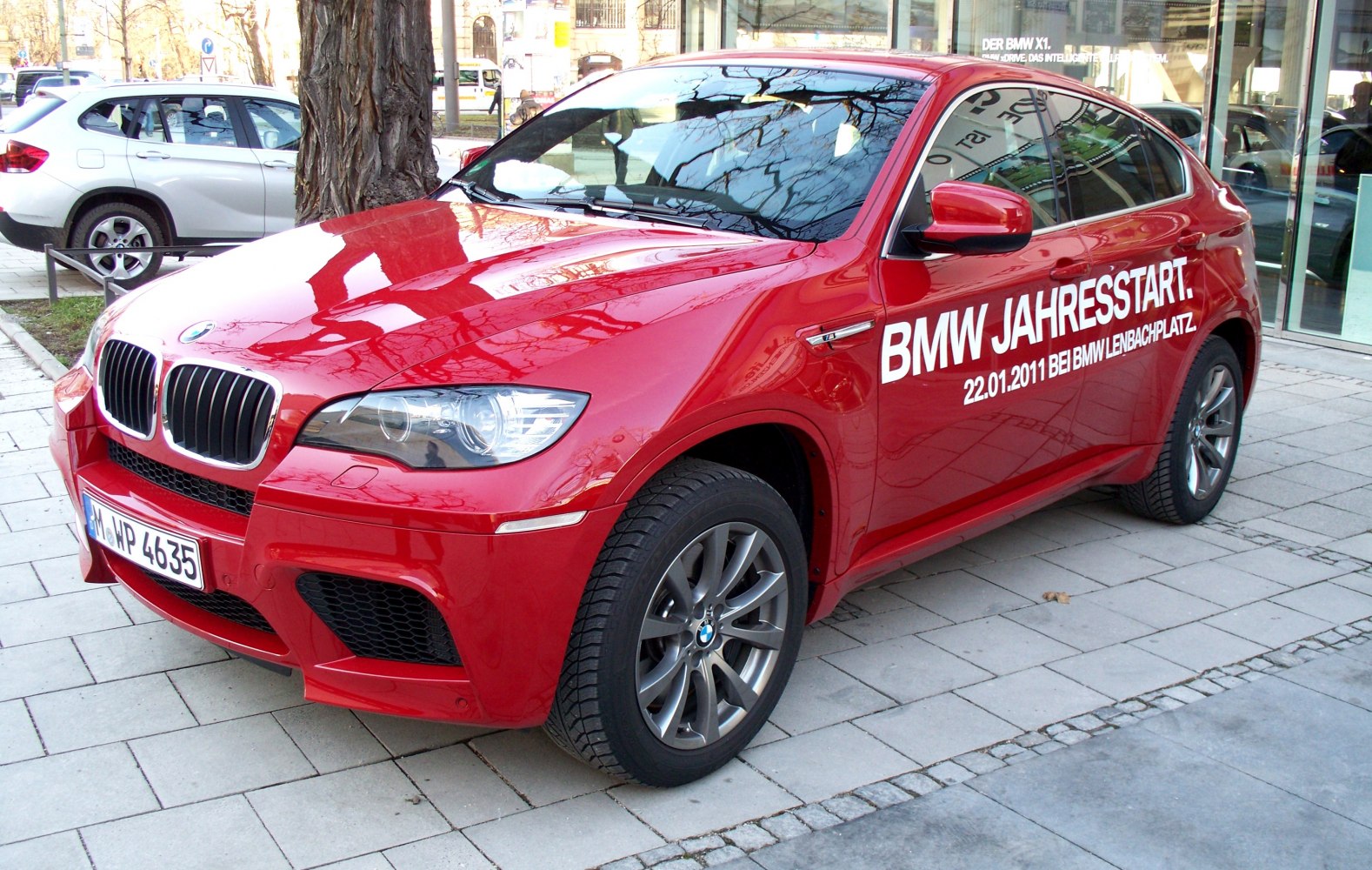 Sporty red crossover front side view with aggressive grille and alloy wheels.