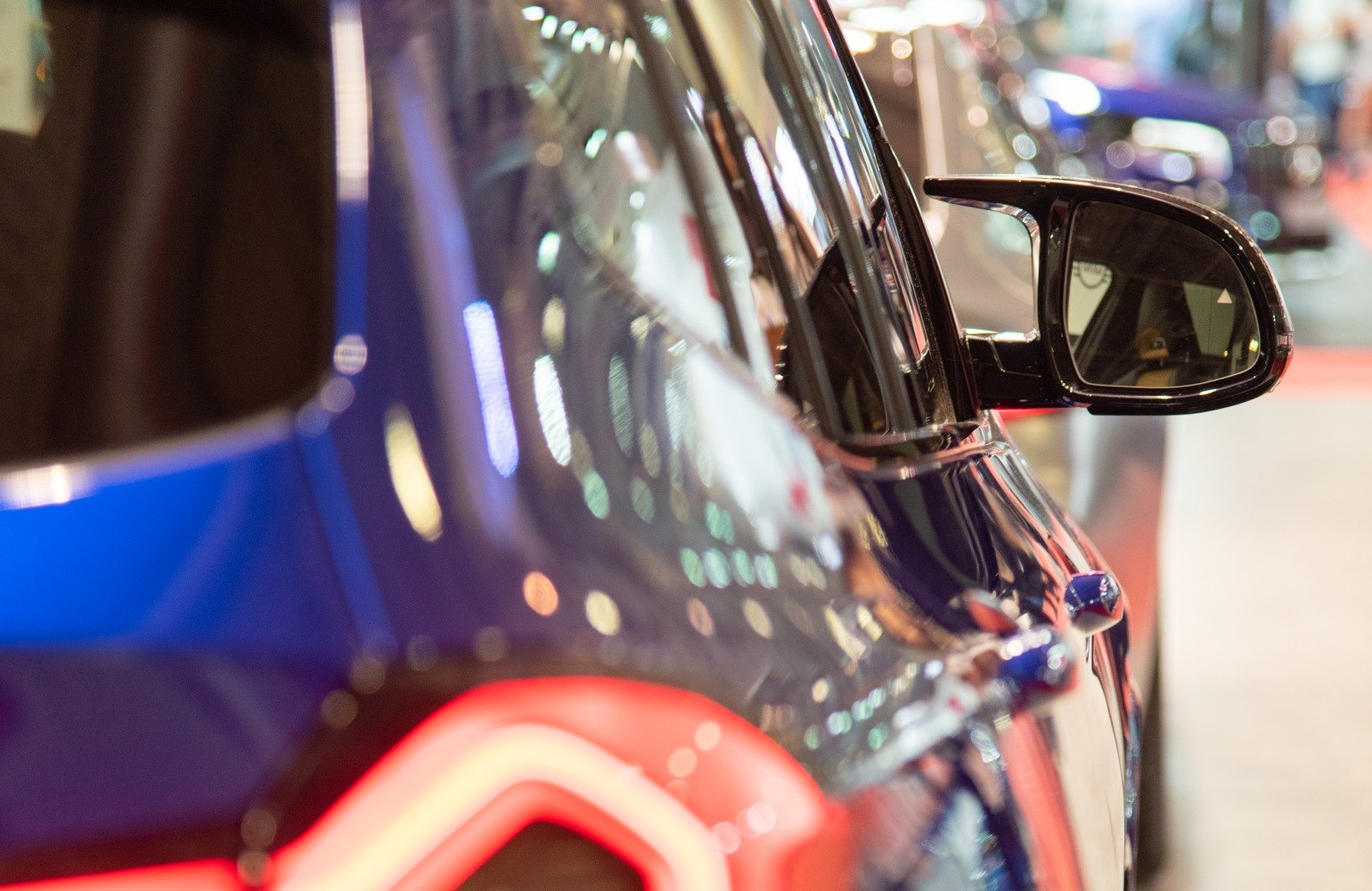 Close-up of side mirror and LED rear taillight with reflective paint surface