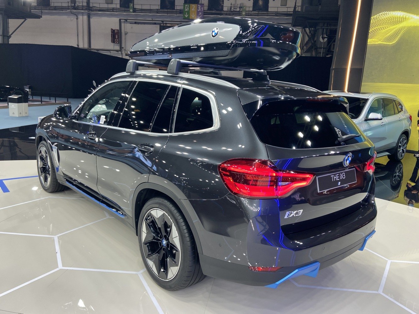 Rear-side view of SUV with rooftop cargo box and illuminated taillights