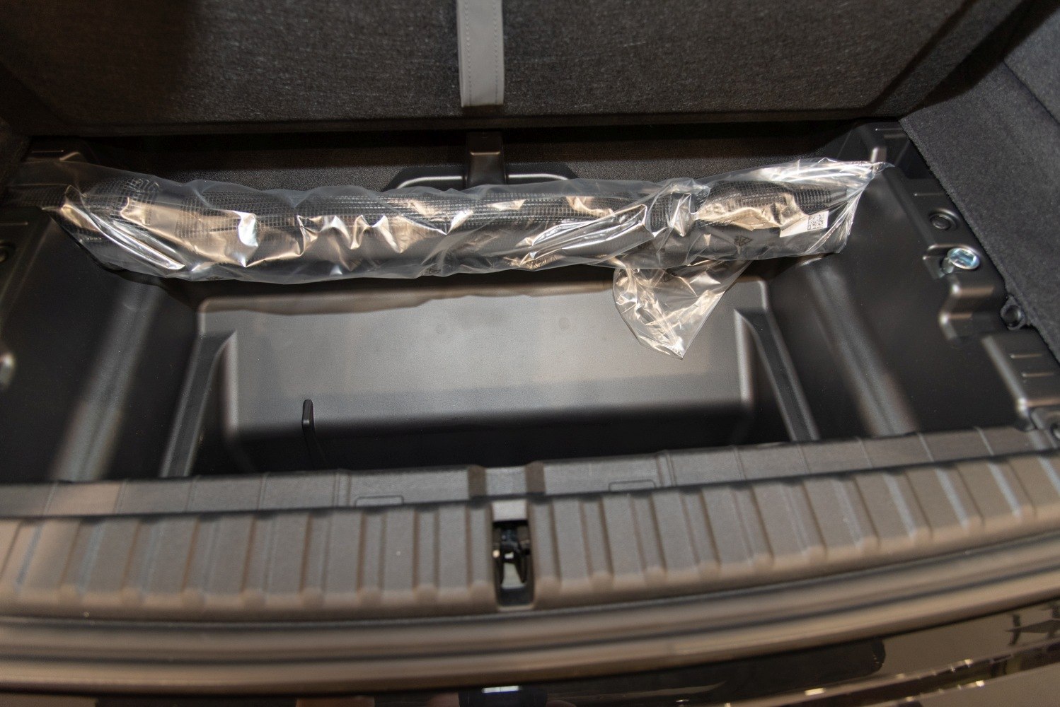 Rear trunk underfloor storage compartment with plastic liner and wrapped accessory
