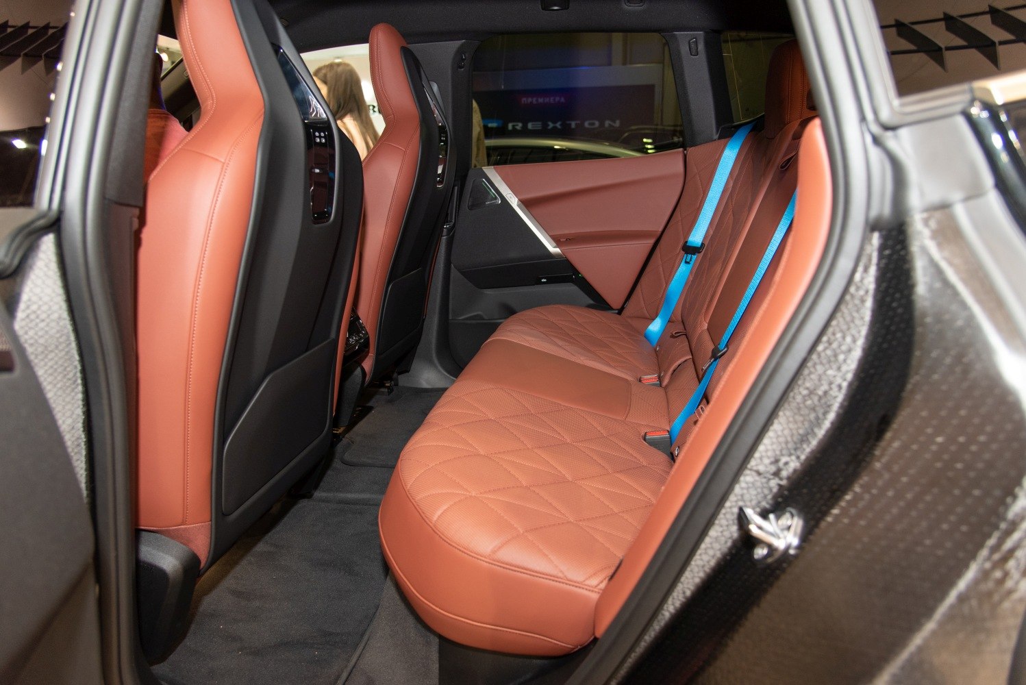 Rear interior with brown quilted leather seats and blue seatbelts