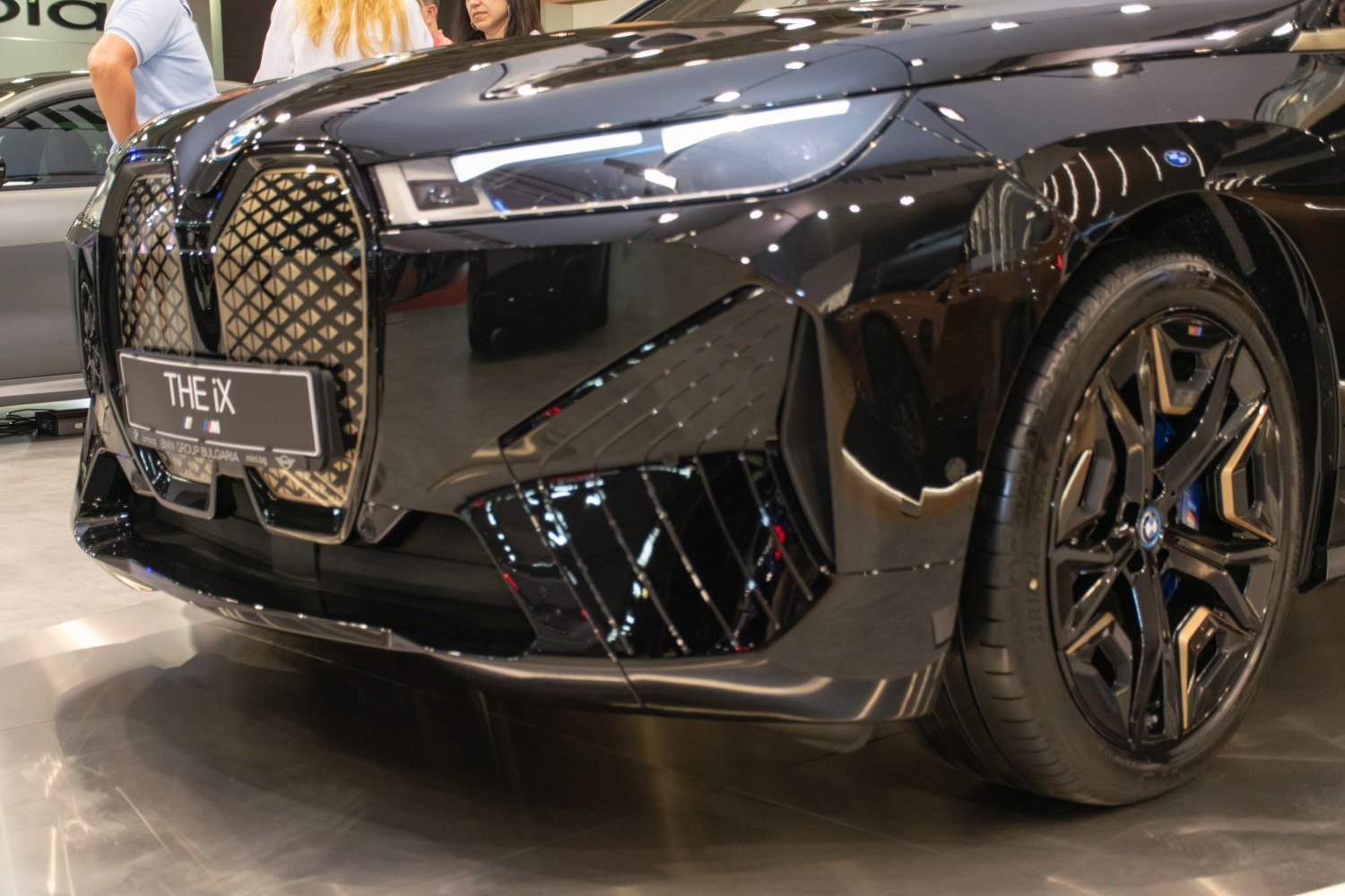 Close-up view of a car's front grille and alloy wheel with detailed modern design.