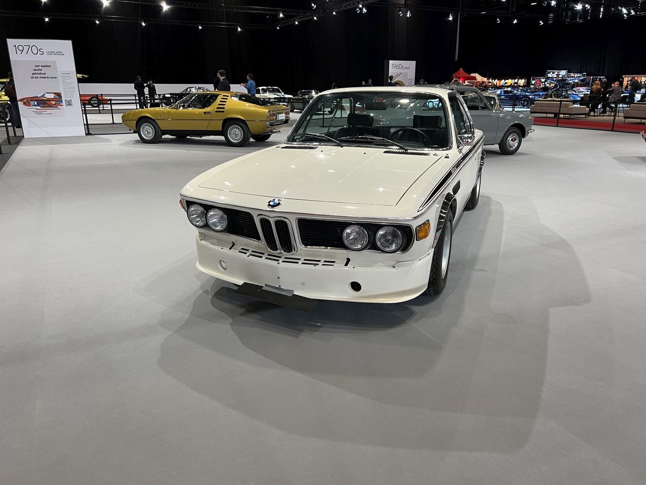 White classic coupe with quad round headlights and kidney grille from the 1970s era
