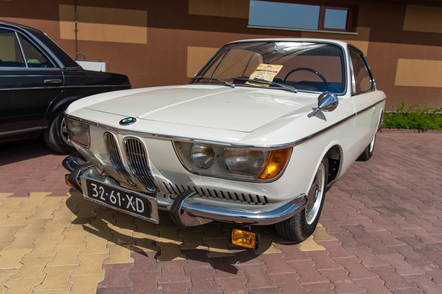 Vintage coupe front with chrome grille, dual headlights, and retro bumper