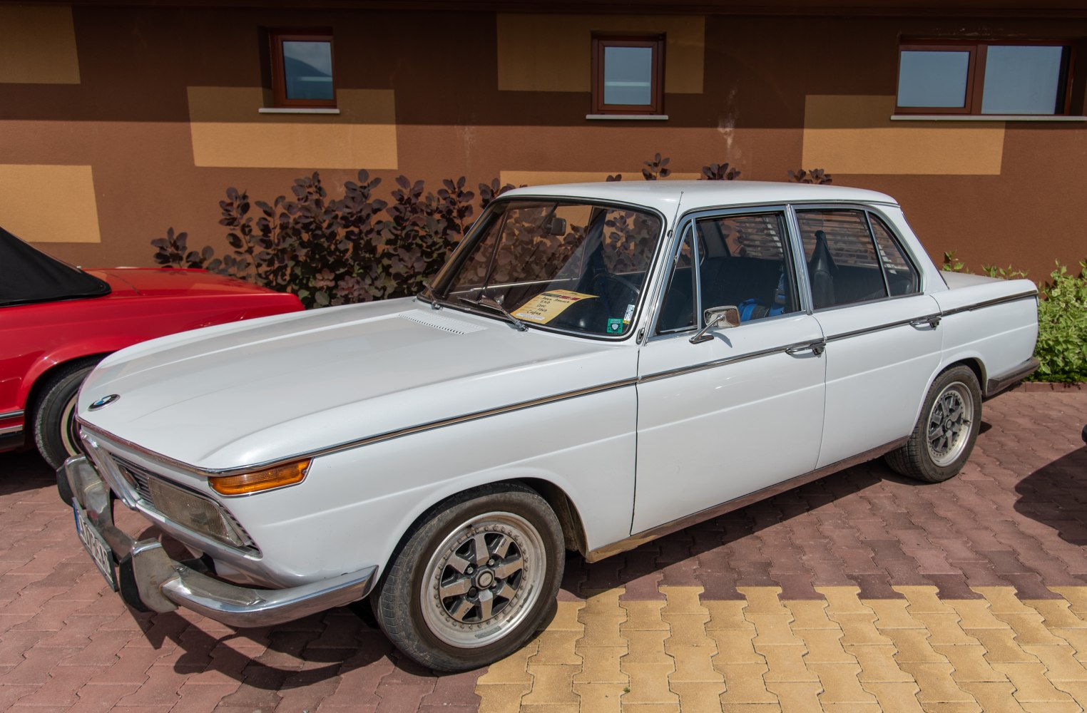 White classic four-door sedan with chrome bumper and vintage rims
