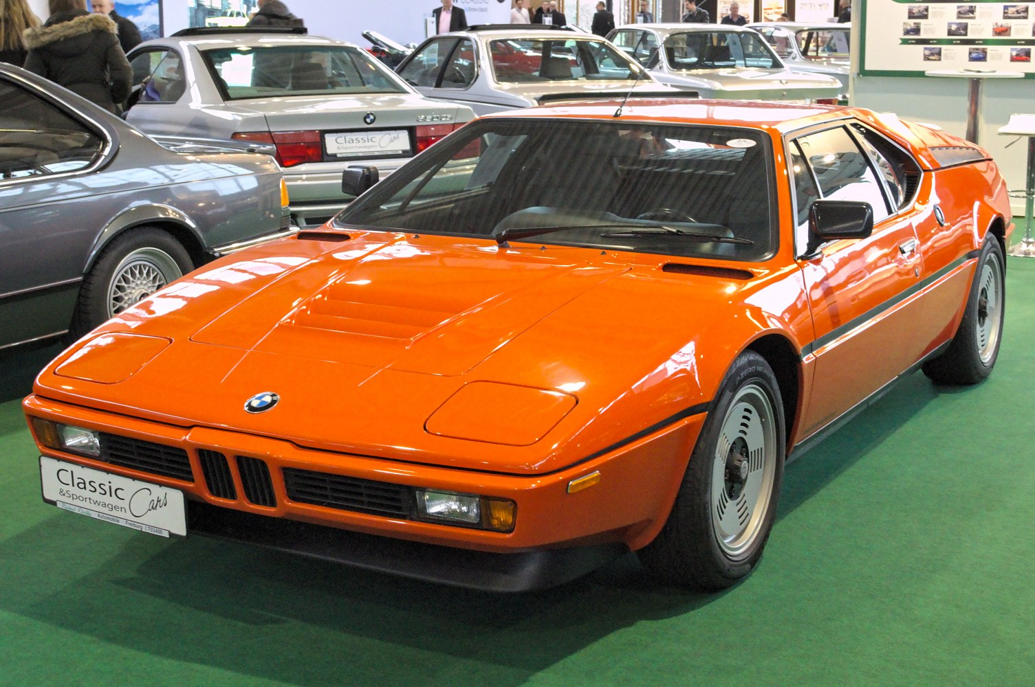 Orange mid-engine sports coupe with pop-up headlights and wedge-shaped body
