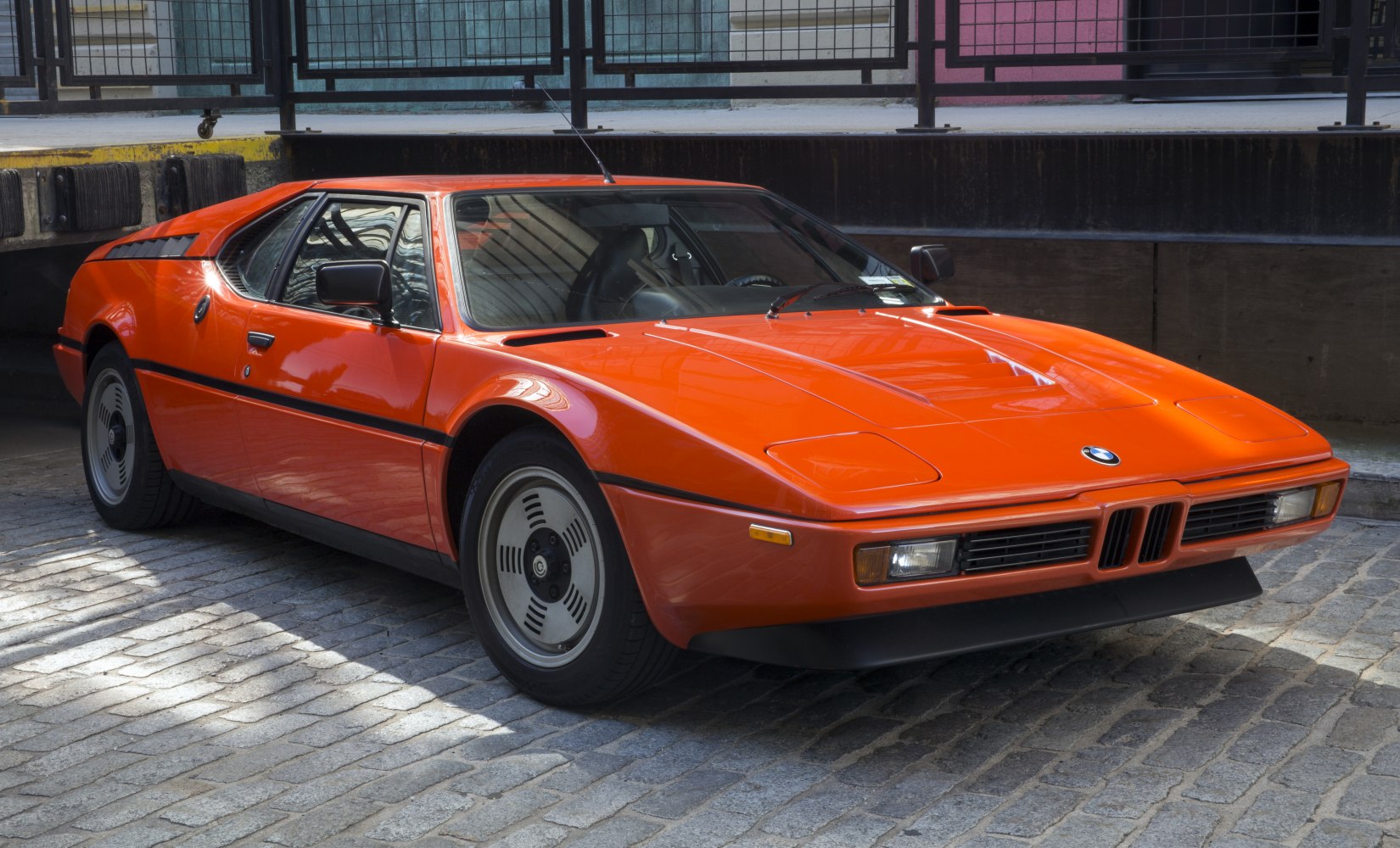 Low-profile orange classic sports coupe with unique wheels and sharp angular design