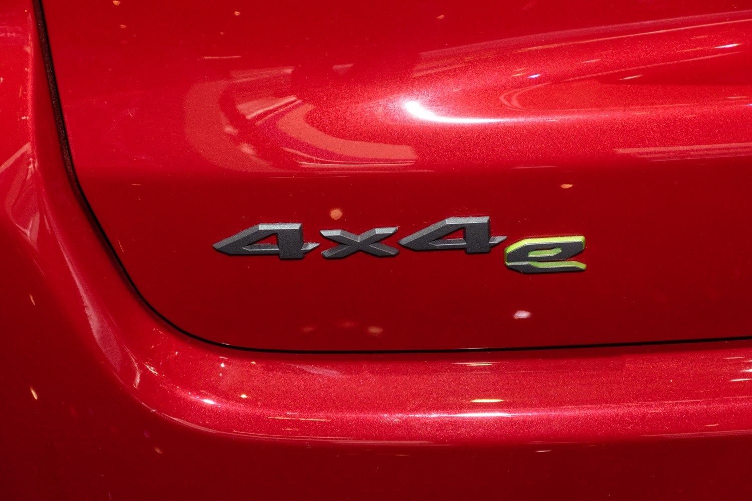 Close-up of a 4x4e hybrid drivetrain emblem on red car body.