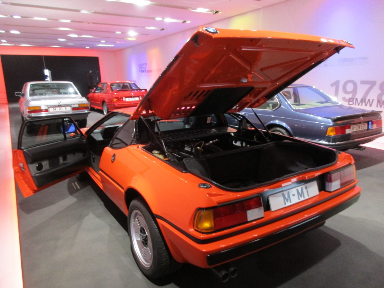 Rear engine compartment and open door of an orange sports car