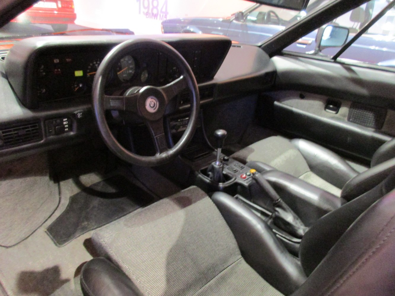 Manual gear shifter and classic three-spoke steering wheel in vintage car interior