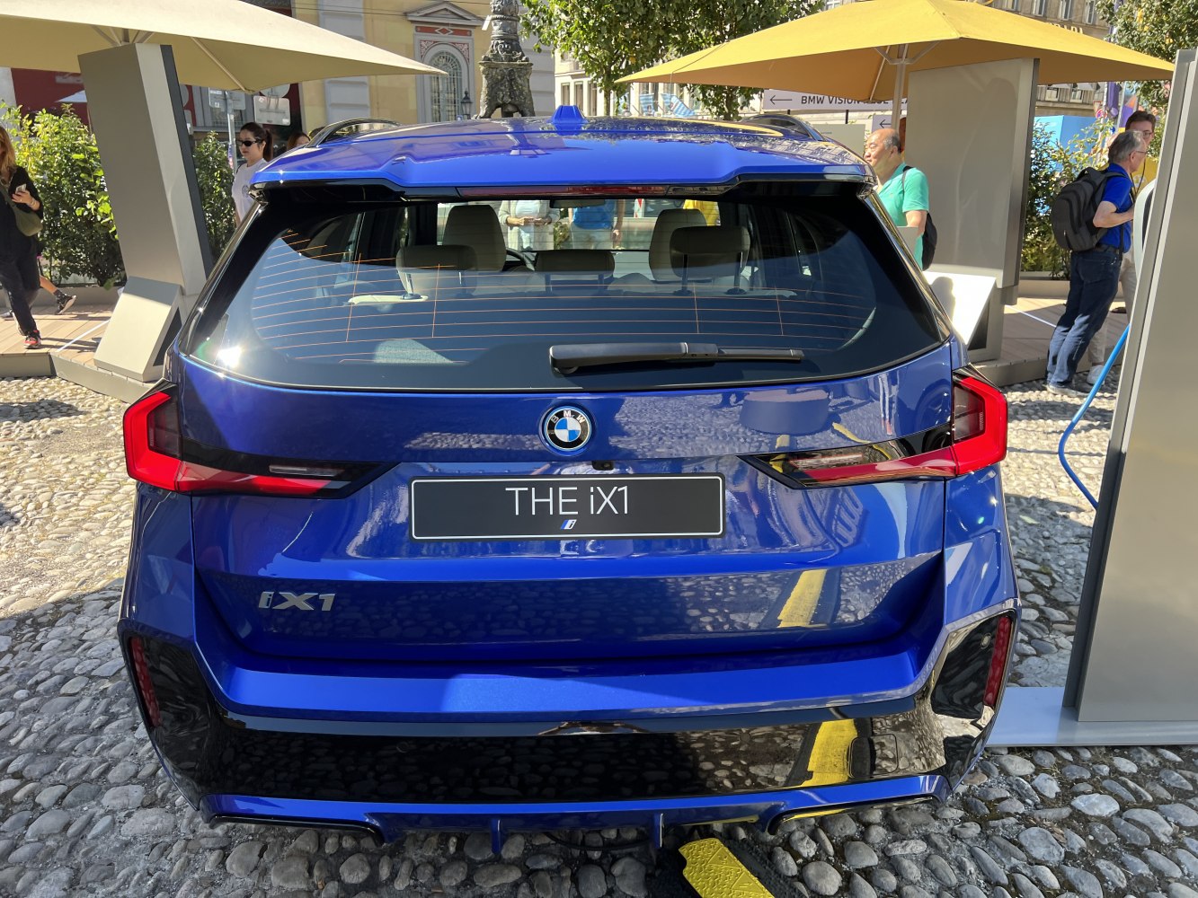 Rear view of a blue electric SUV with distinctive LED tail lights and rear windshield wiper.