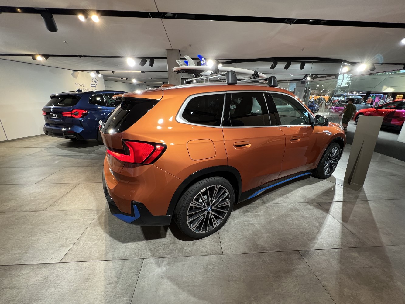 Orange electric SUV rear view with roof rack and sporty taillights