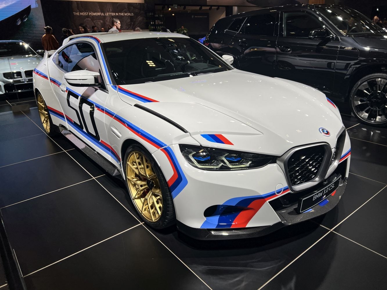 White coupe with racing stripes, blue and red accents, and gold alloy wheels