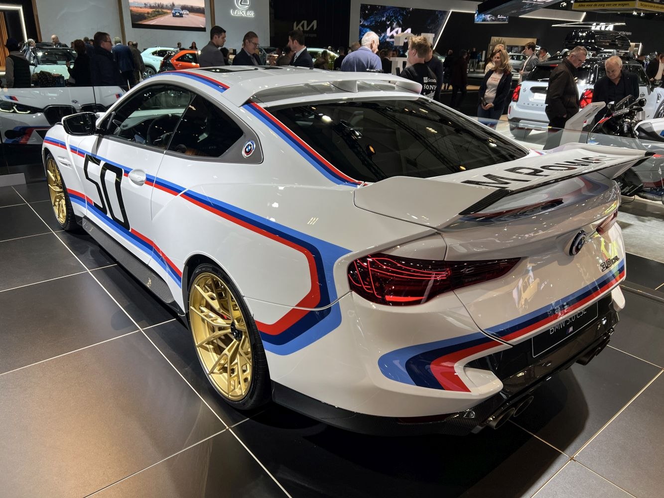 Sports coupe with racing livery, gold wheels, and large rear wing