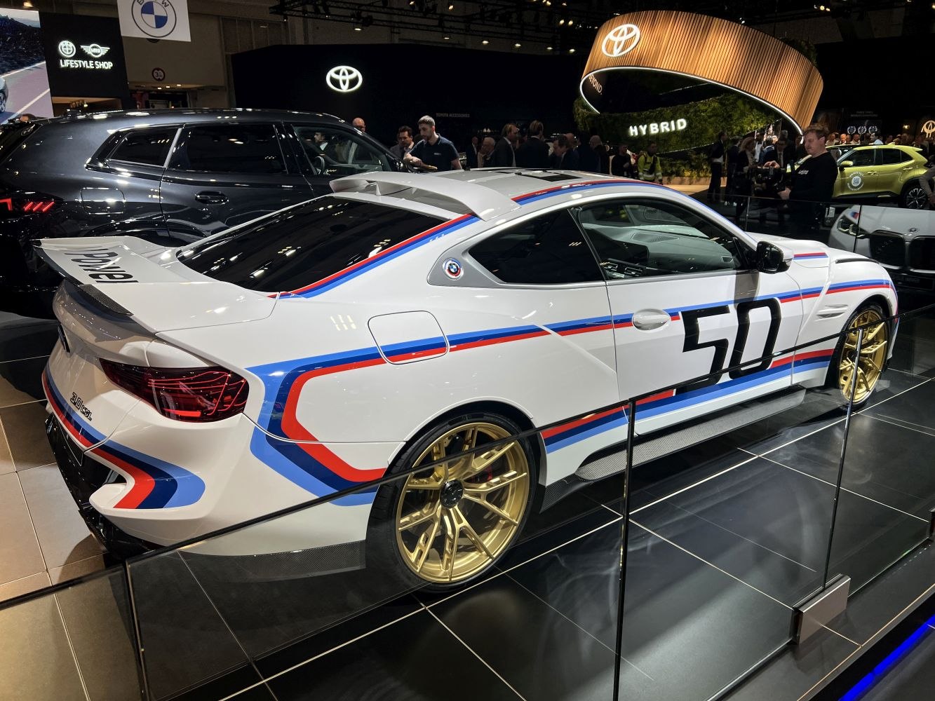 White sports coupe with racing stripes, large rear wing, and gold wheels