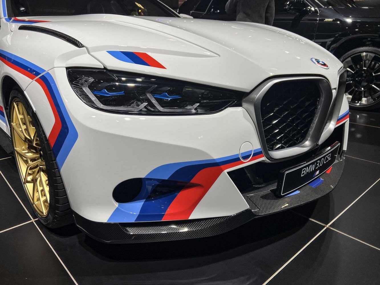 Aggressive front headlights, signature kidney grille, M stripes, and gold wheels.