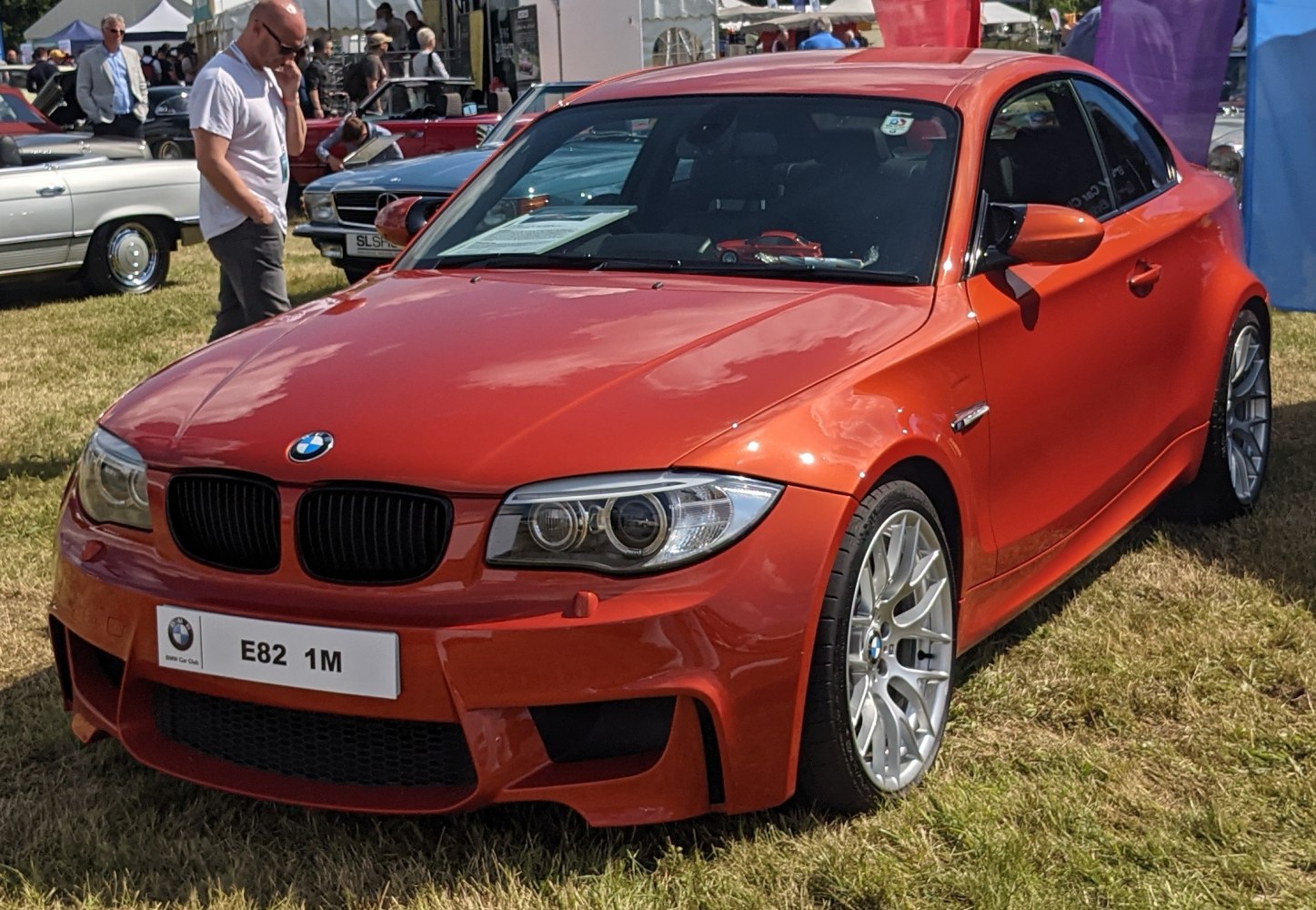 Front view of an orange sporty coupe with aggressive fascia and alloy wheels.