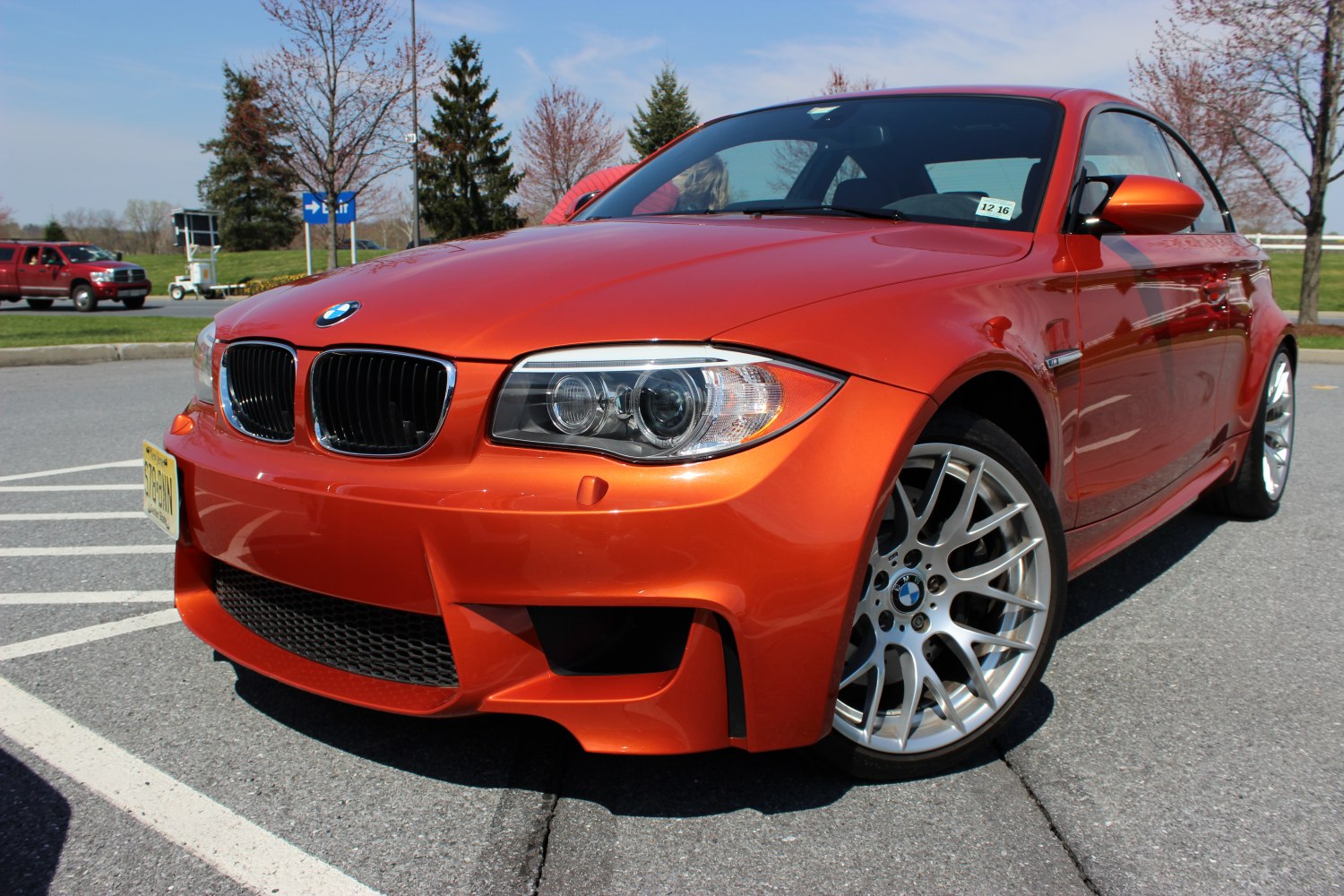 Bright orange sporty coupe front with aggressive styling and alloy wheels