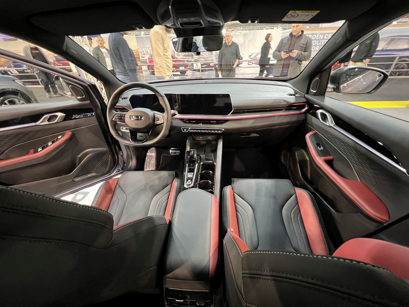 Modern dashboard with digital display, black-red sporty seats.