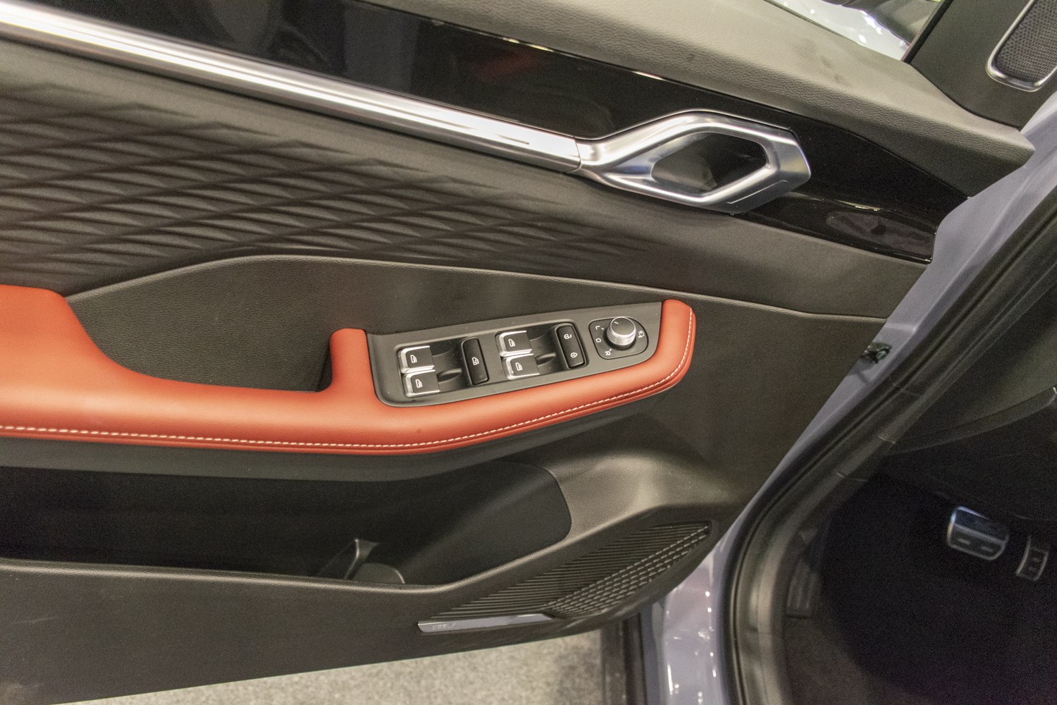 Car door panel with control buttons and red stitched armrest