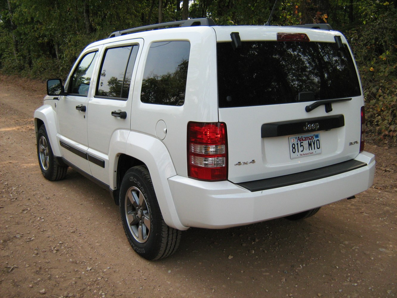 Rear view of white SUV with 4x4 badge parked on dirt road
