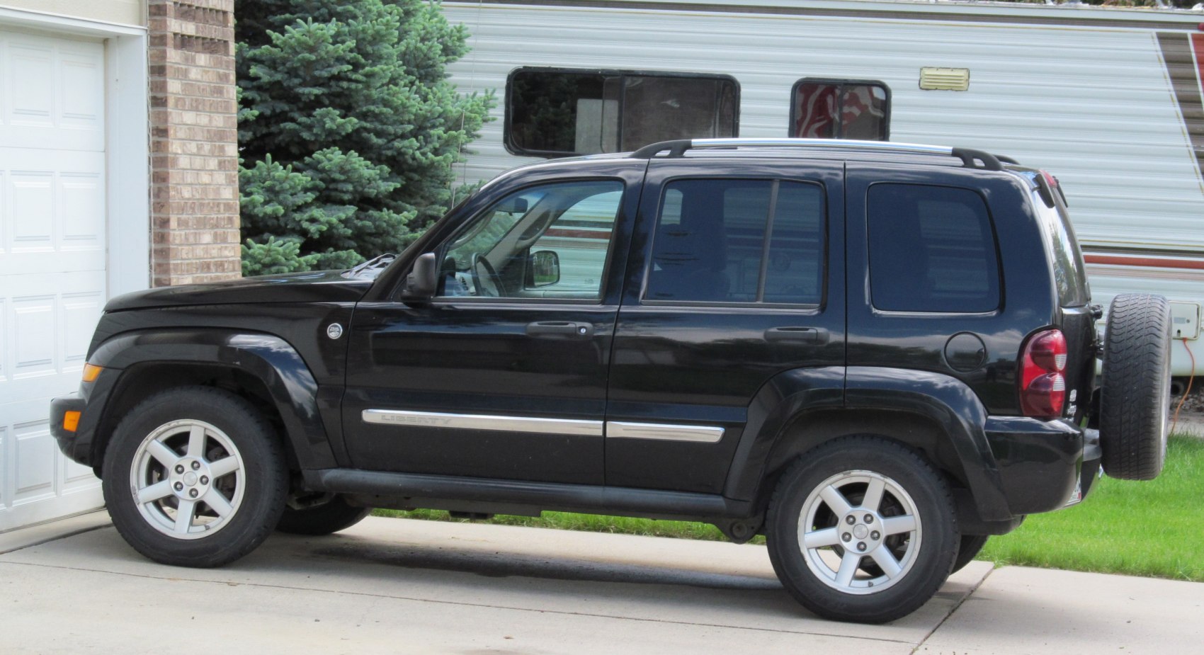 Black SUV side profile with roof rails and rear-mounted spare tire