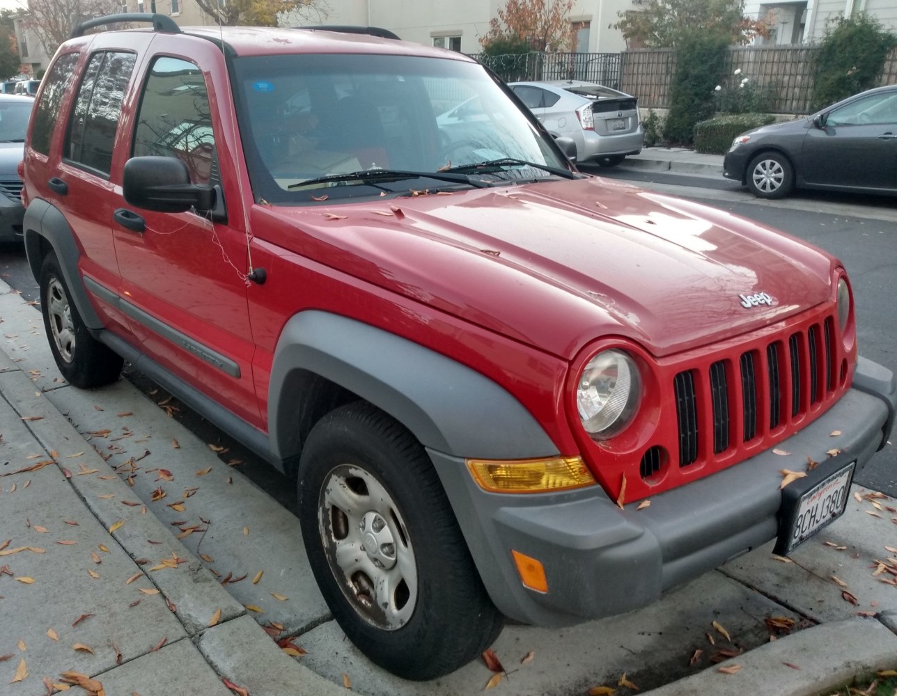 Red SUV front-side with rounded headlights and vertical grille bars