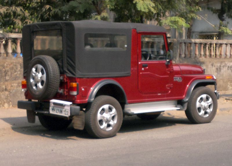 Red SUV with soft top viewed from rear side with alloy wheels and rugged design