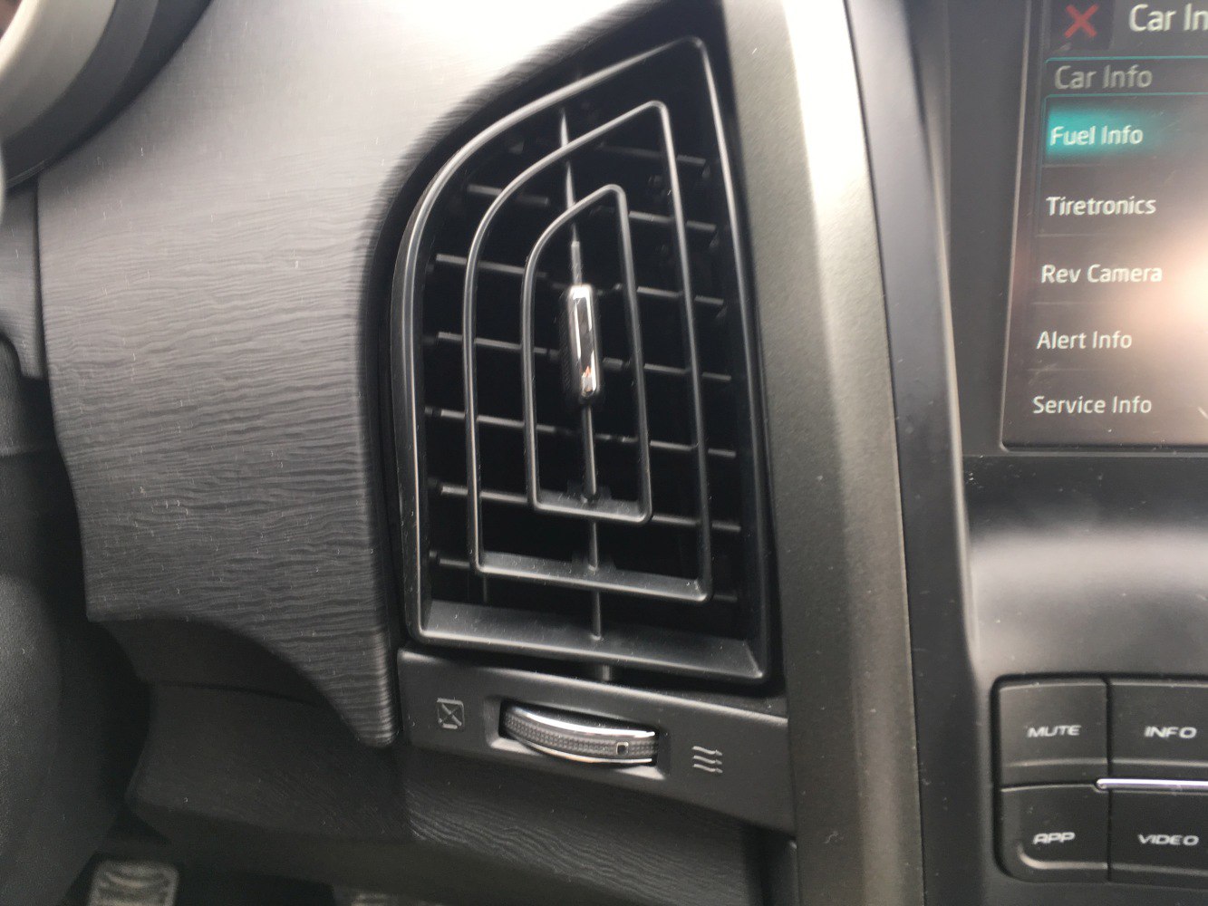 Close-up of air vent with adjacent infotainment control buttons