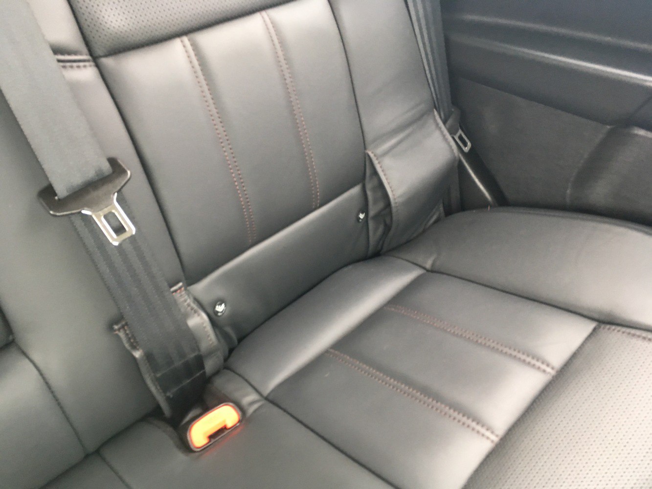 Black leather rear seat upholstery with seatbelt and stitching.