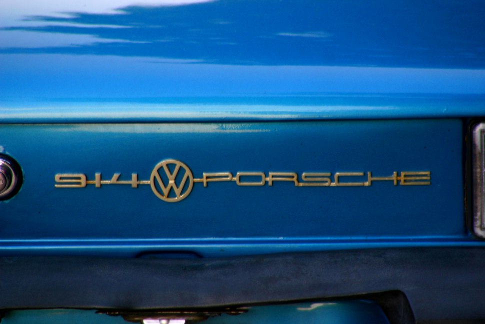 Close-up of gold VW-Porsche 914 rear emblem on blue surface