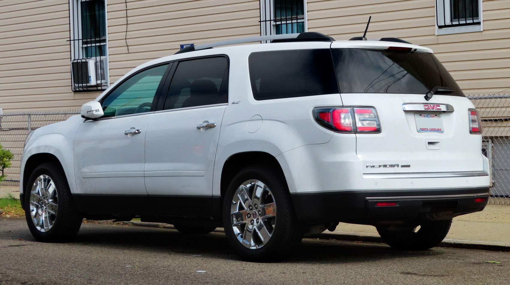 Rear and side exterior of a white SUV with polished wheels and tinted windows