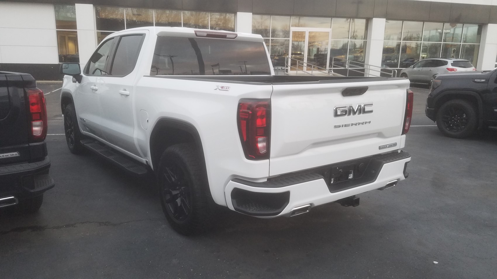 Rear and side view of a white pickup truck with black wheels and distinctive taillights