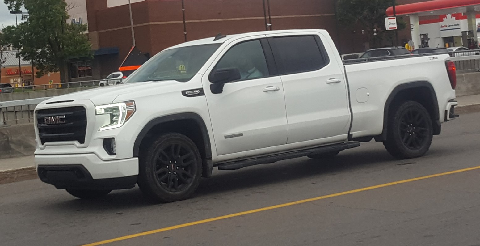 White pickup with crew cab, black wheels, and side steps
