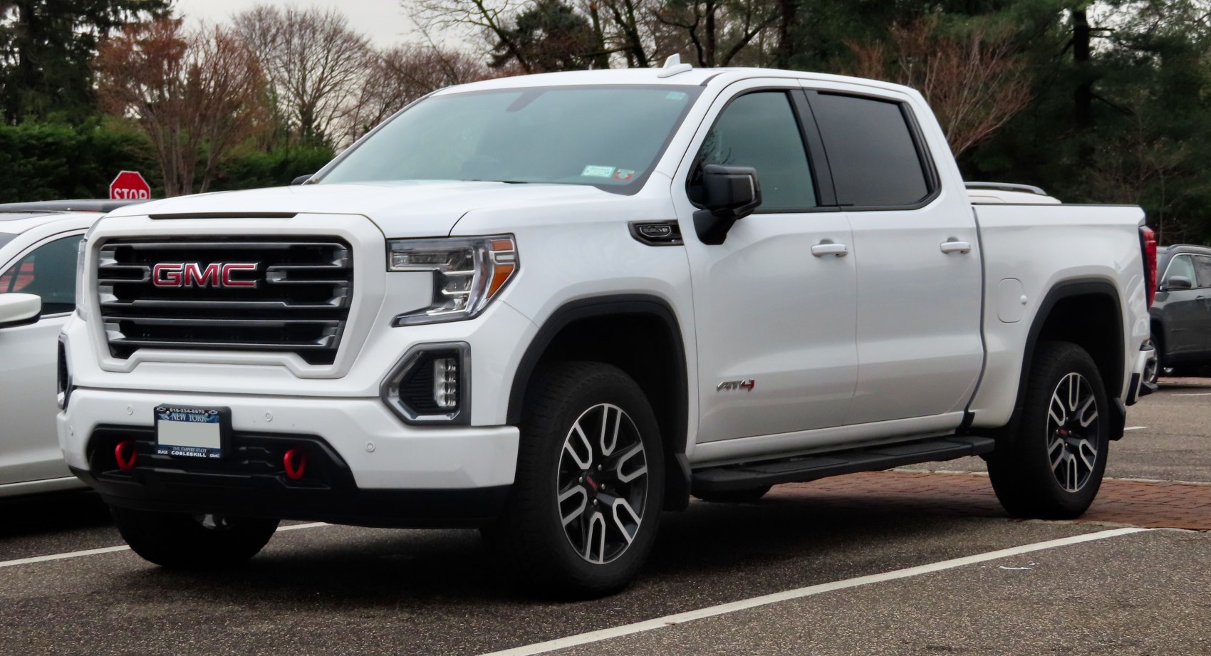 Front view and side profile of a crew cab short box pickup truck with bold grille and AT4 badging