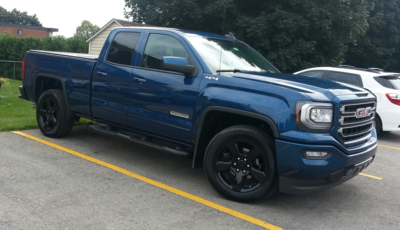 Blue pickup truck with double cab and black rims parked in lot