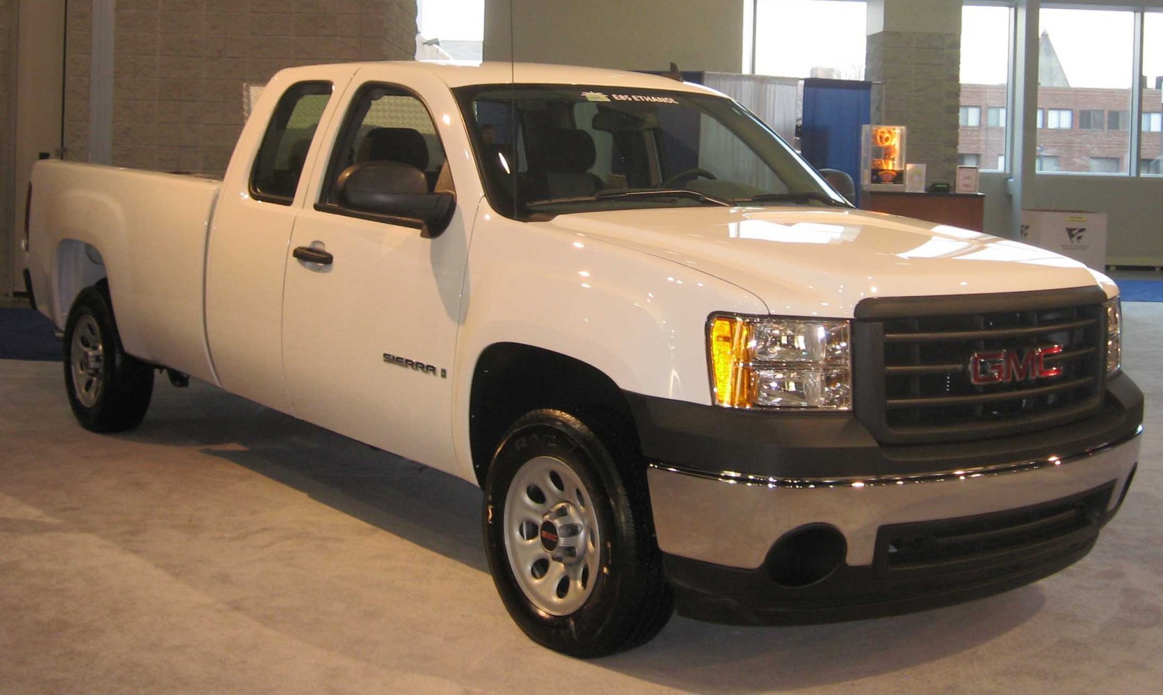 White extended cab pickup with long bed and black grille