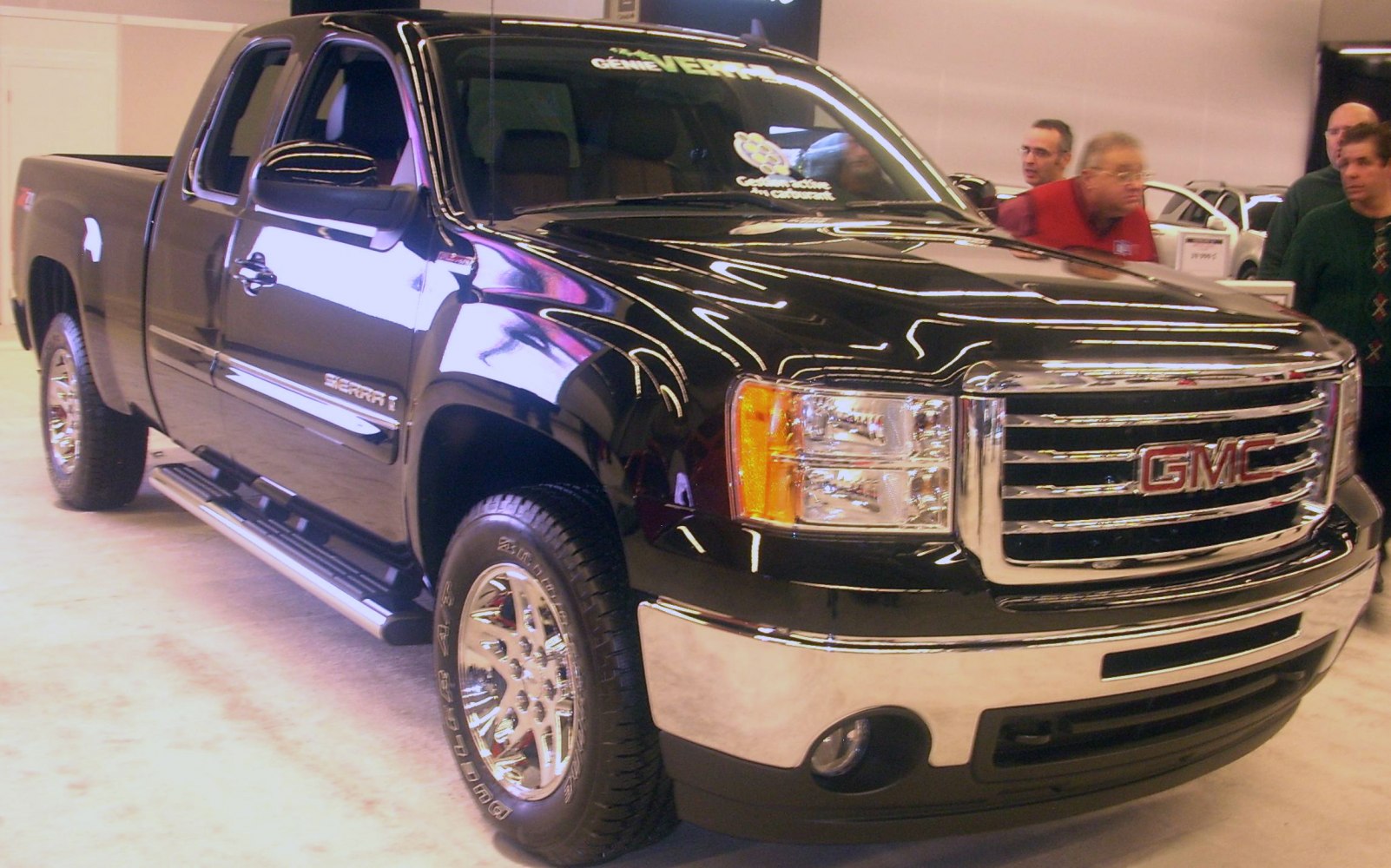 Front and side profile of a black extended cab pickup with chrome grille and polished wheels.