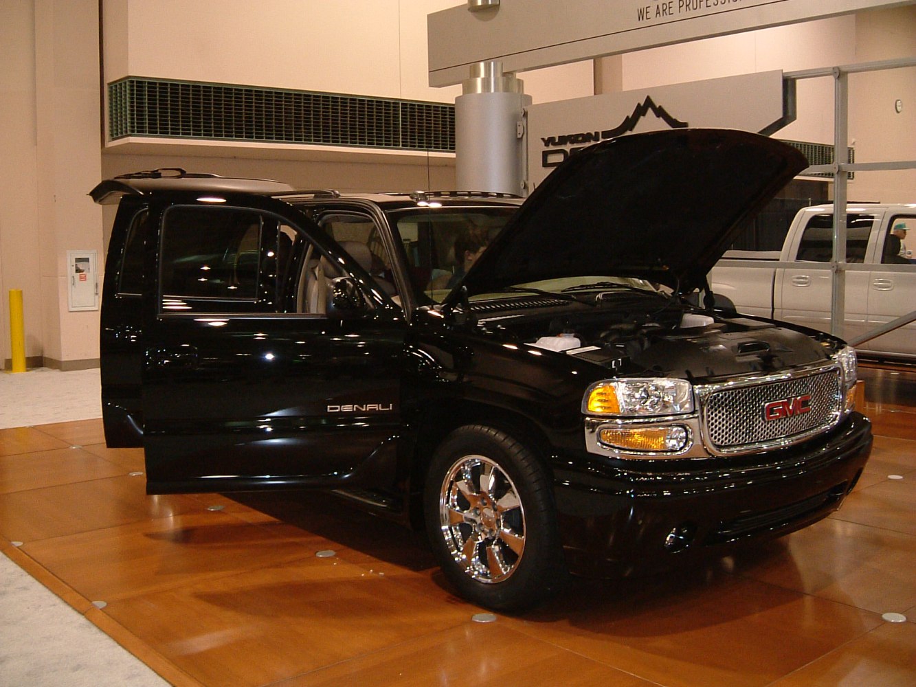 Open hood and driver door on black SUV with chrome wheels