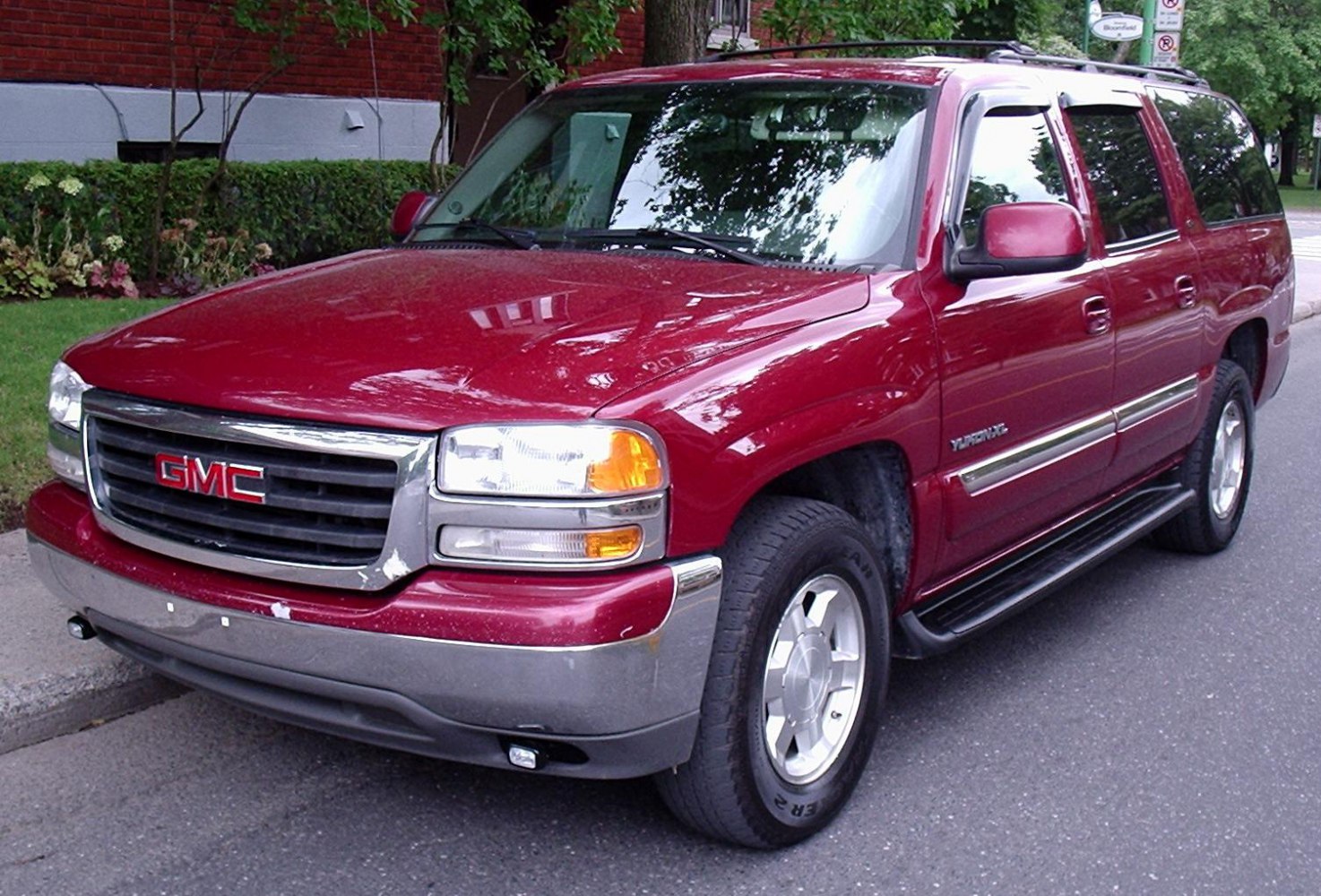 Front and side view of red SUV with chrome grille and running boards