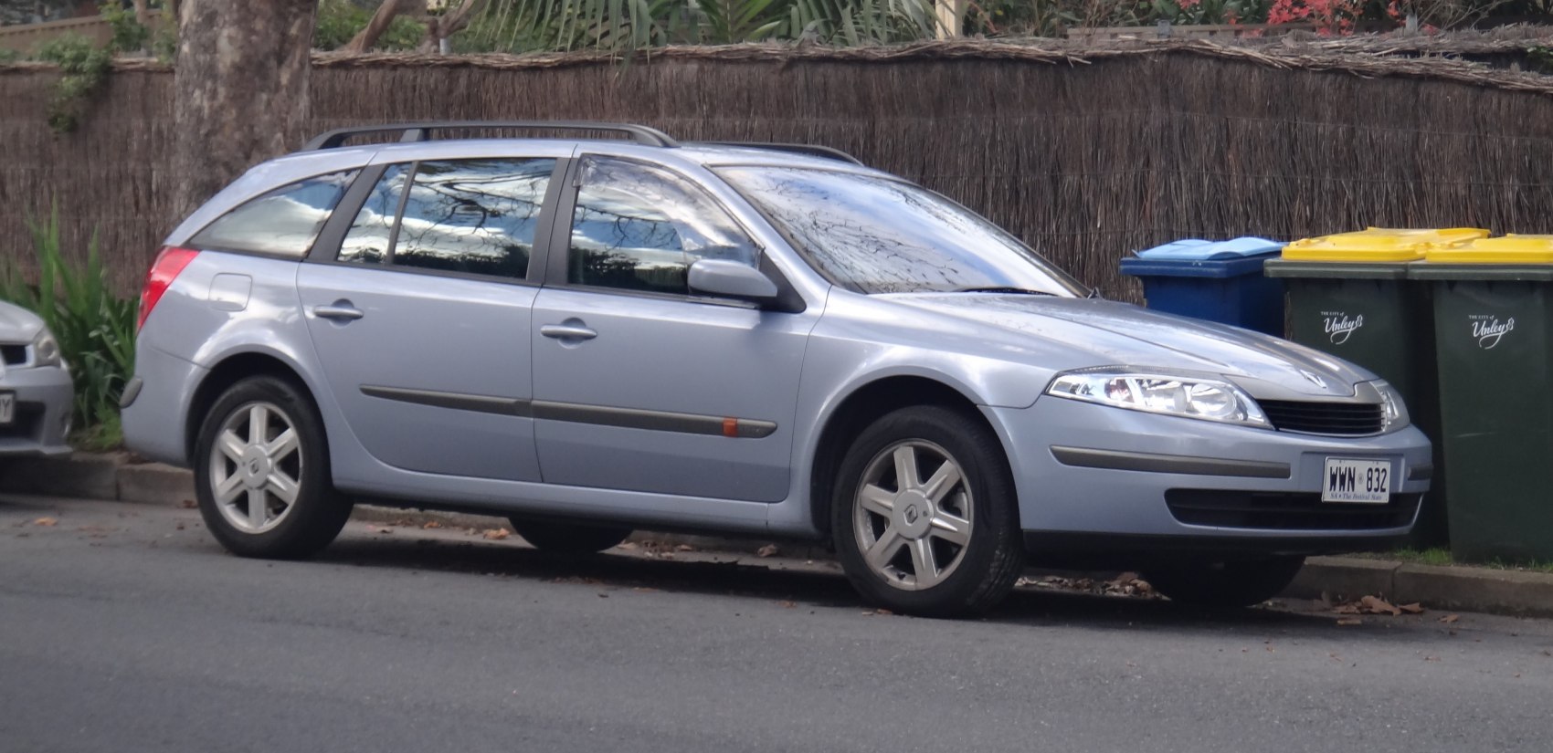 Silver estate car with roof rails and five-spoke wheels parked on street.