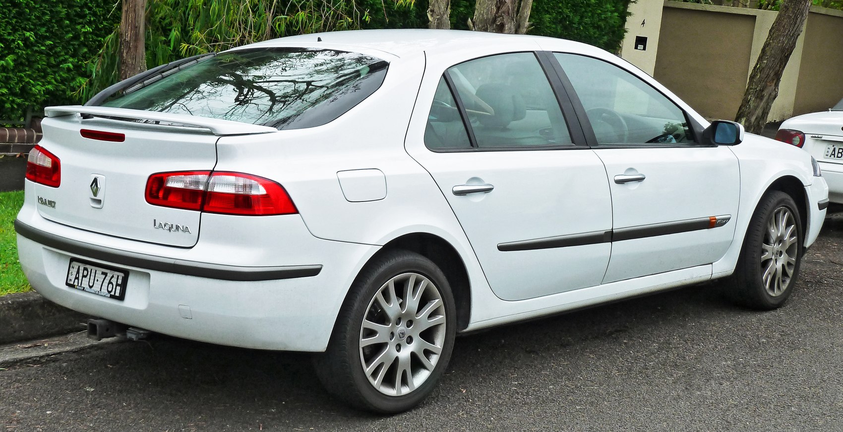 White sedan rear side view with spoiler and alloy wheels