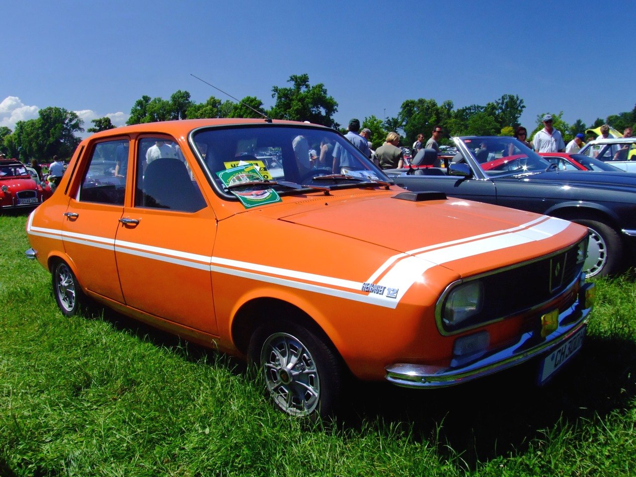 Orange vintage four-door sedan with racing stripes and alloy wheels