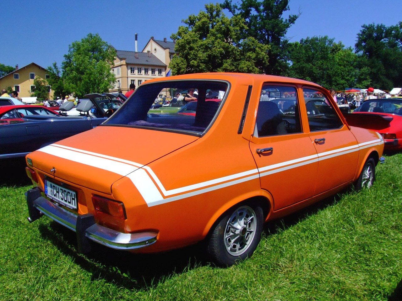 Orange four-door sedan with white racing stripes and vintage styled rims