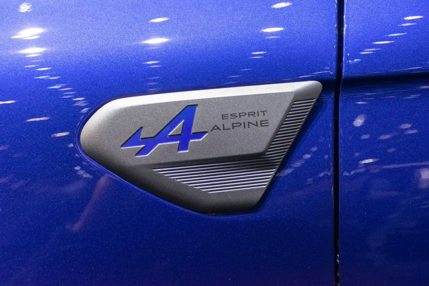 Close-up of Esprit Alpine badge with blue stylized 'A' on metallic surface